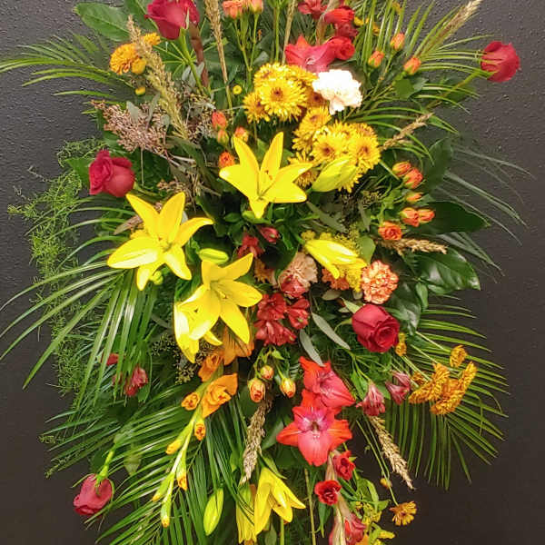 Large standing spray with red roses, yellow lilies, and mixed blooms