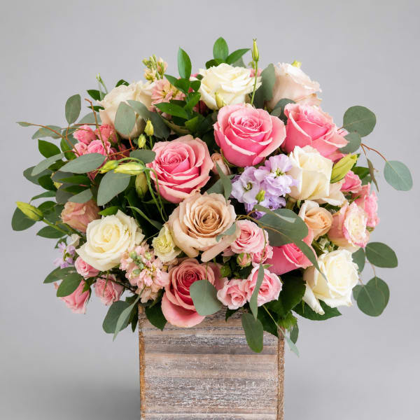 Pink and cream roses arranged in a wooden box
