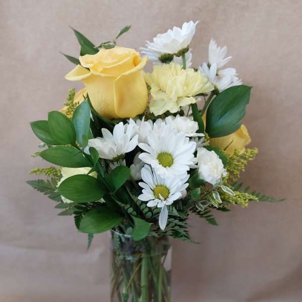 Yellow roses and white daisies in a clear glass vase