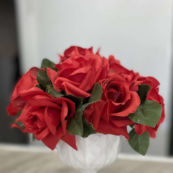 Red roses arranged in a white goblet vase