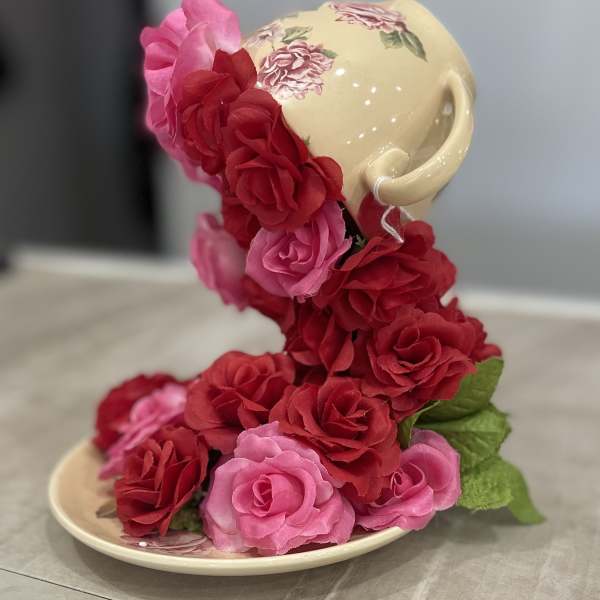 Ceramic teacup and saucer covered with pink and red roses