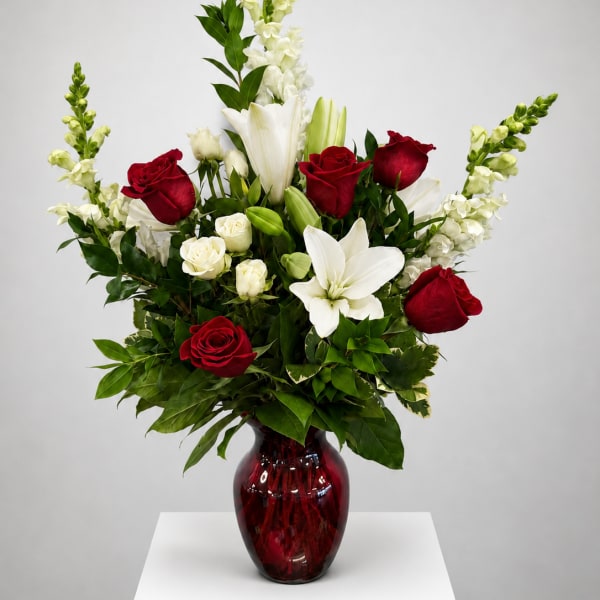 Red and white floral arrangement in a red glass vase