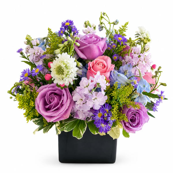 Mixed bouquet of purple, pink, and blue flowers in a black vase