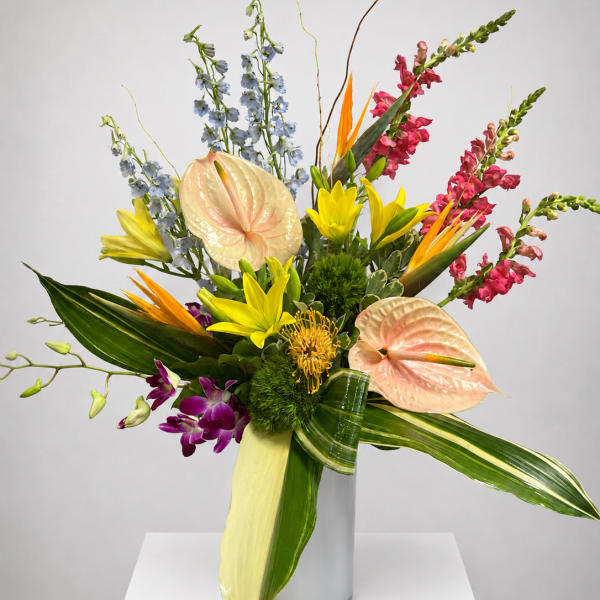 Tropical bouquet with anthuriums, orchids, lilies, and snapdragons in a glass vase