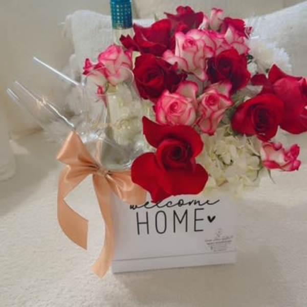 Box of red and pink roses with a wine bottle and ribbon