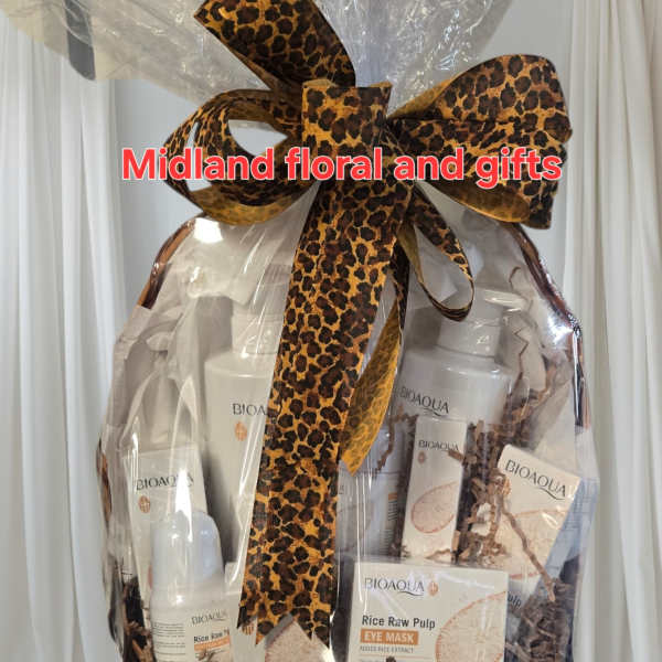 Gift basket with skincare products wrapped in clear cellophane and a leopard-print bow