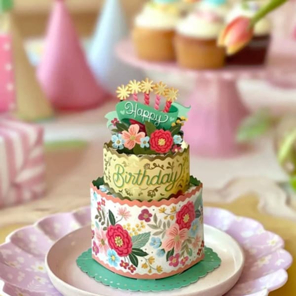 Tiered birthday cake with floral decorations and pastel party accents