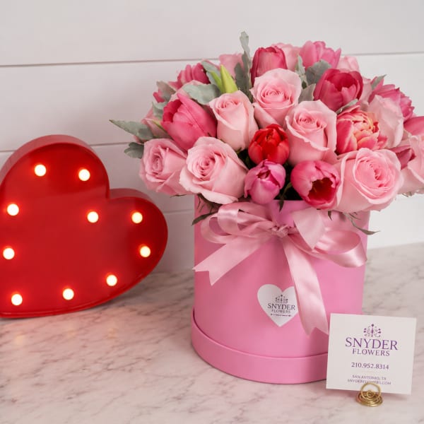 Pink roses and tulips in a pink hat box with a ribbon