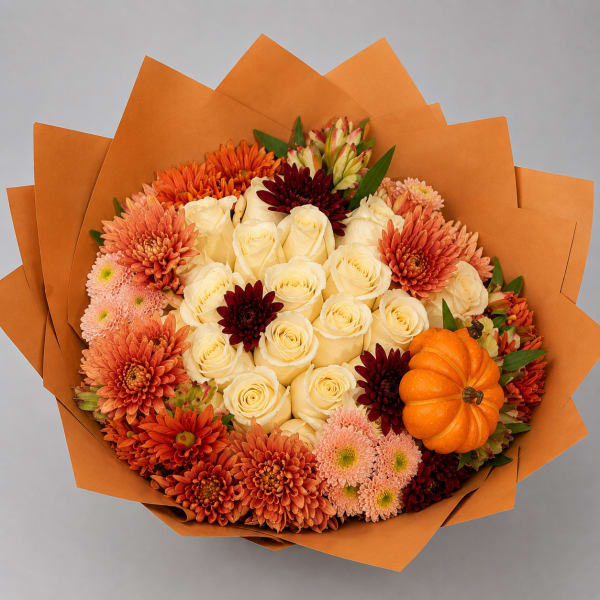 Bouquet of cream roses, orange chrysanthemums, and a small pumpkin wrapped in orange paper