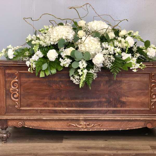 White floral arrangement on a wooden chest with curly branches
