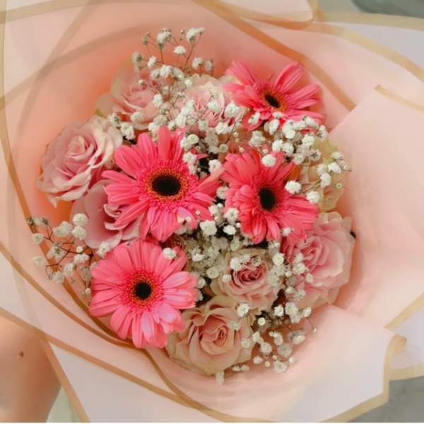 Pink gerbera daisies and roses wrapped in pale peach paper