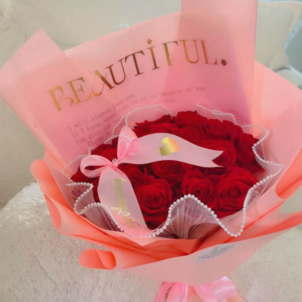 Bouquet of red roses wrapped in pink paper with a ribbon