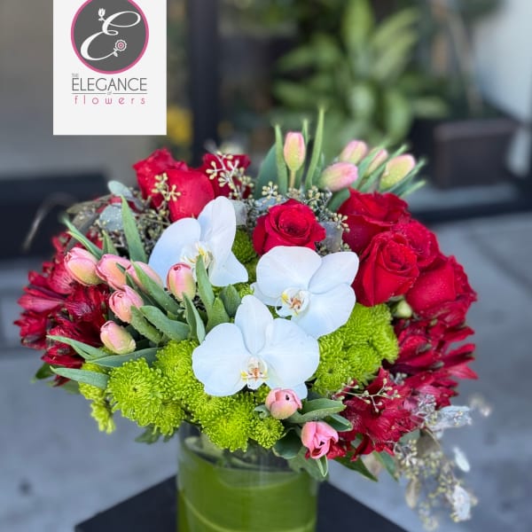Red roses, white orchids, and green mums in a glass vase