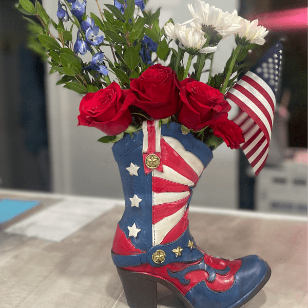 Red roses and white daisies arranged in a patriotic cowboy boot vase