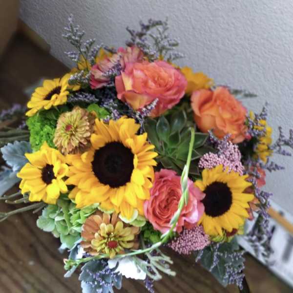 Bouquet of sunflowers and pink-orange roses with mixed filler flowers
