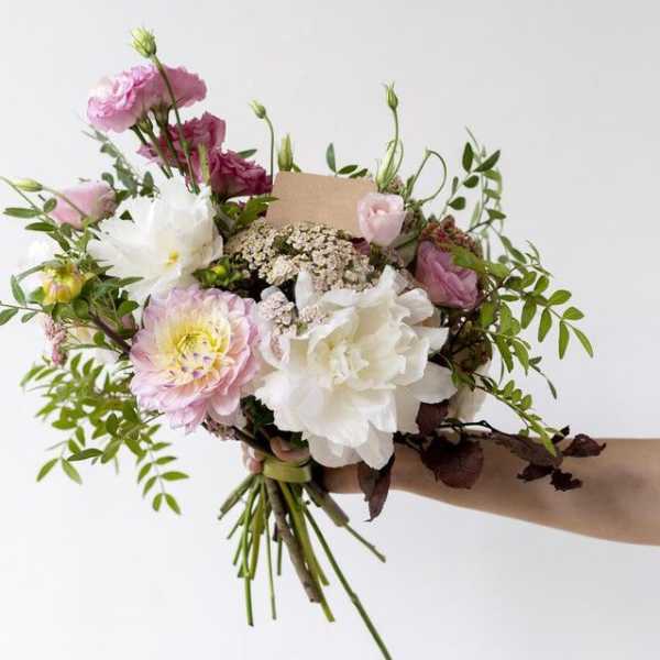 Handheld bouquet of pink and white flowers with airy greenery