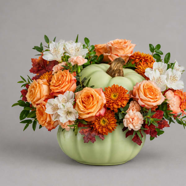 Orange and white flowers arranged in a pumpkin-shaped vase
