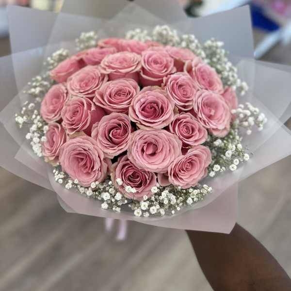 Bouquet of pink roses with white baby's breath in translucent wrap