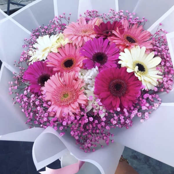 Bouquet of pink, white, and magenta gerbera daisies wrapped in white paper