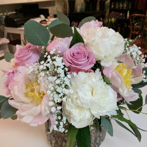 Pink and white bouquet with roses and peonies in a rustic vase