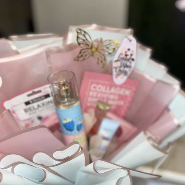 Pink gift basket with skincare items and a butterfly decoration