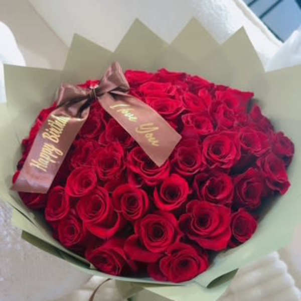 Bouquet of red roses wrapped in pale green paper with a ribbon