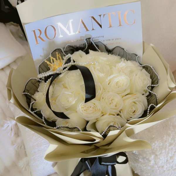 Bouquet of white roses wrapped in cream paper with black ribbon