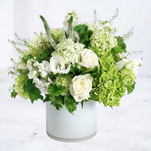 White and green floral arrangement in a white cylindrical vase