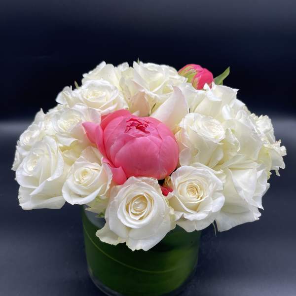 White roses and a pink peony in a green glass vase