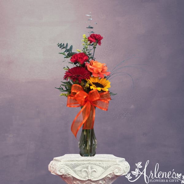 Tall mixed bouquet in a glass vase with a large orange ribbon