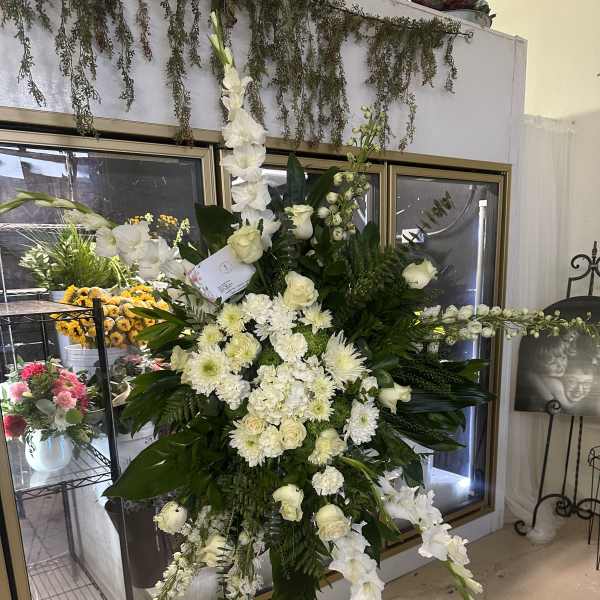 Large white funeral spray on a stand with cascading flowers