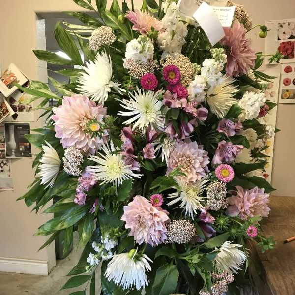 Large standing floral spray with pink, white, and lavender blooms