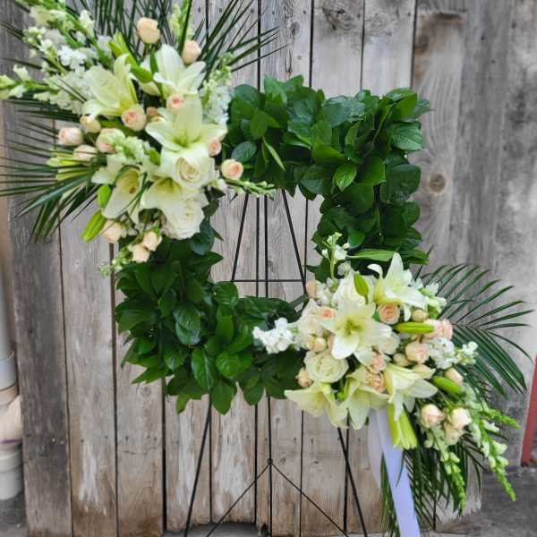 Large floral wreath on a stand with white lilies and pale roses