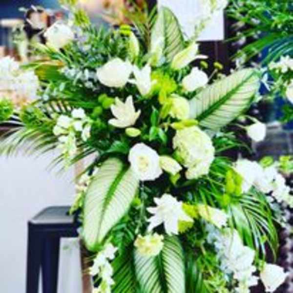 Tall white floral arrangement with large tropical leaves