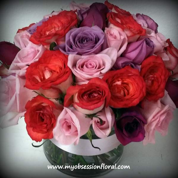 Bouquet of red, pink, and purple roses in a glass vase