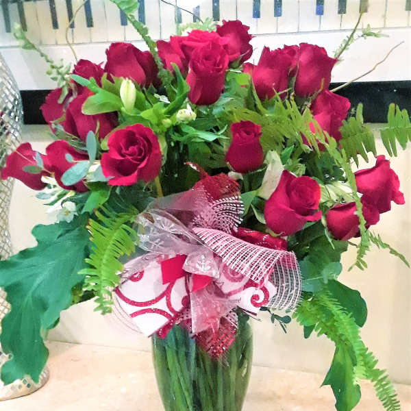 Bouquet of red roses in a green glass vase with a pink ribbon