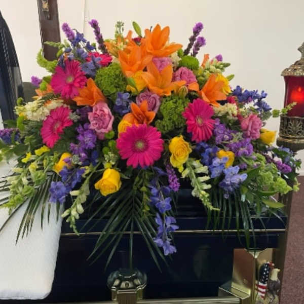 Colorful funeral spray with orange lilies, pink daisies, and purple flowers