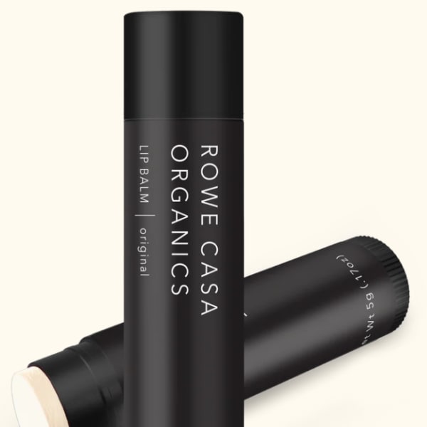 Three black lip balm tubes, one standing upright and two lying behind it
