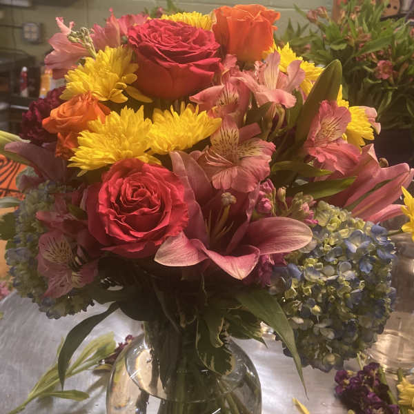 Mixed bouquet of roses, lilies, chrysanthemums, and hydrangeas in a glass vase