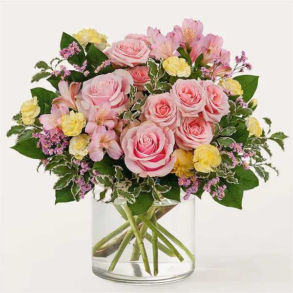 Pink roses and yellow carnations in a clear glass vase