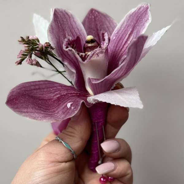 Purple orchid corsage held in a hand