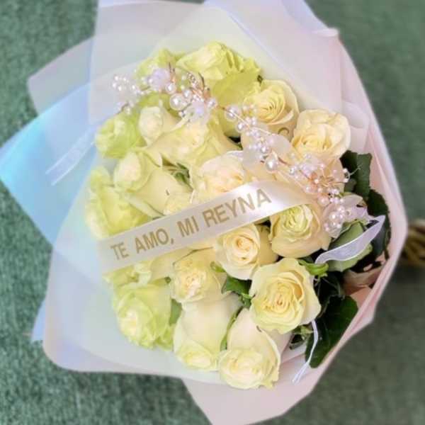 Bouquet of pale yellow roses wrapped in pastel paper with a decorative ribbon