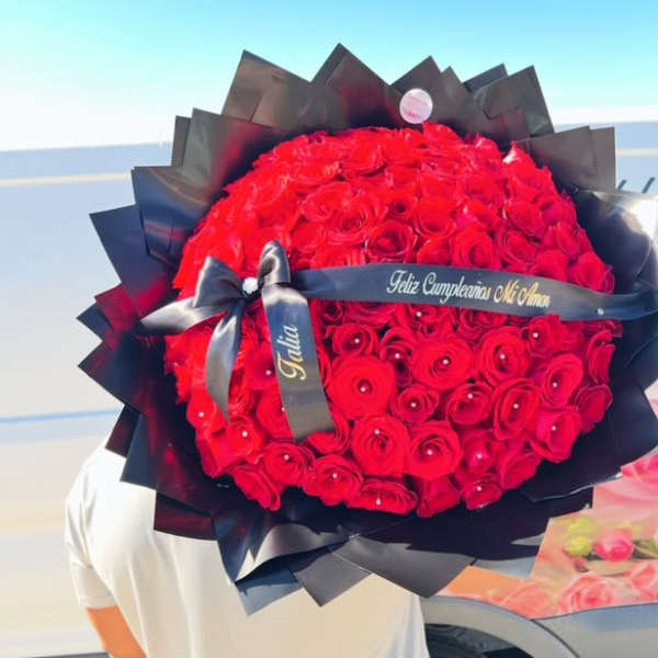 Large bouquet of red roses wrapped in black paper with a ribbon