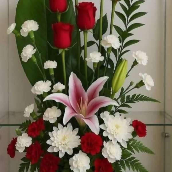 Red roses, white carnations, and a pink lily in a black vase