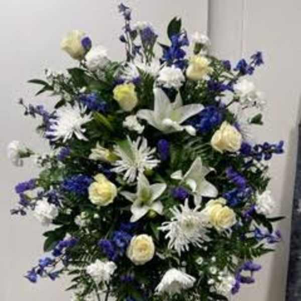 Standing floral spray with white and blue flowers on a metal easel