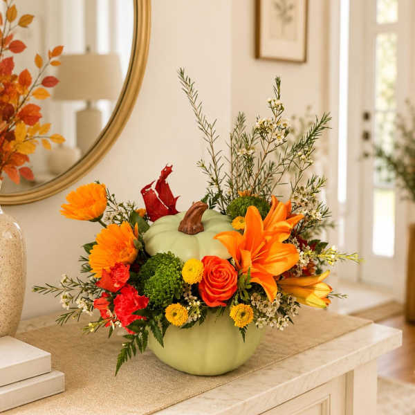 Pumpkin-shaped floral arrangement with orange and red blooms in a vase