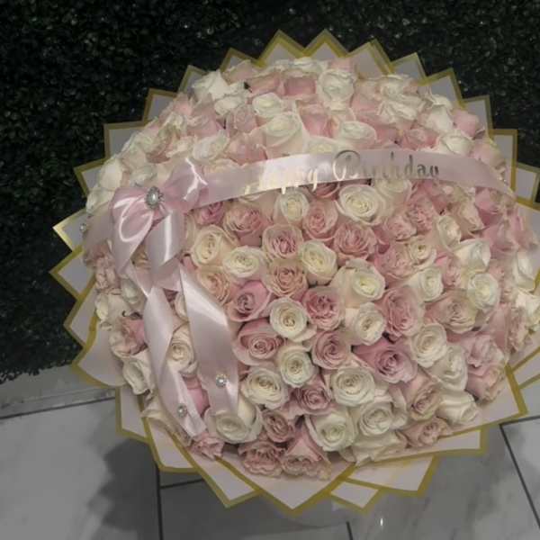 Large round bouquet of pale pink and white roses with a pink ribbon
