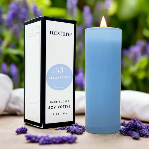 Blue votive candle beside its box with purple flowers in the background