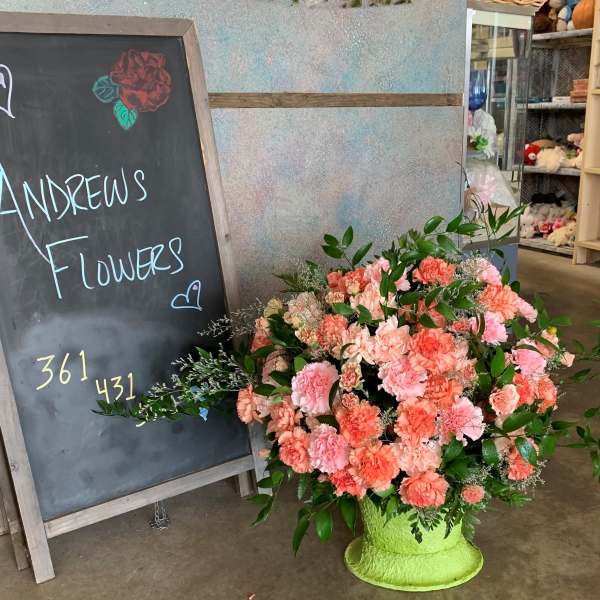 Large peach and pink carnation arrangement in a bright green vase