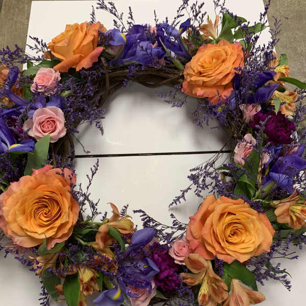 Circular floral wreath with orange roses, purple flowers, and pink accents